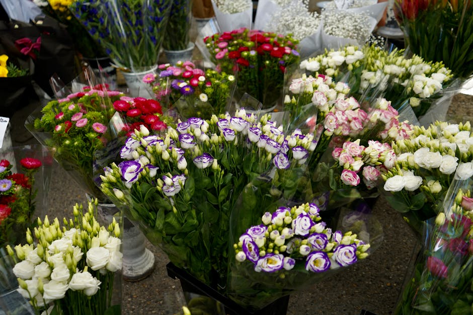 A variety of fresh floral bouquets arranged on a display table at a flower shop, featuring an assortment of flowers in vibrant colors. Prominent among them are purple and white Lisianthus, with tightl